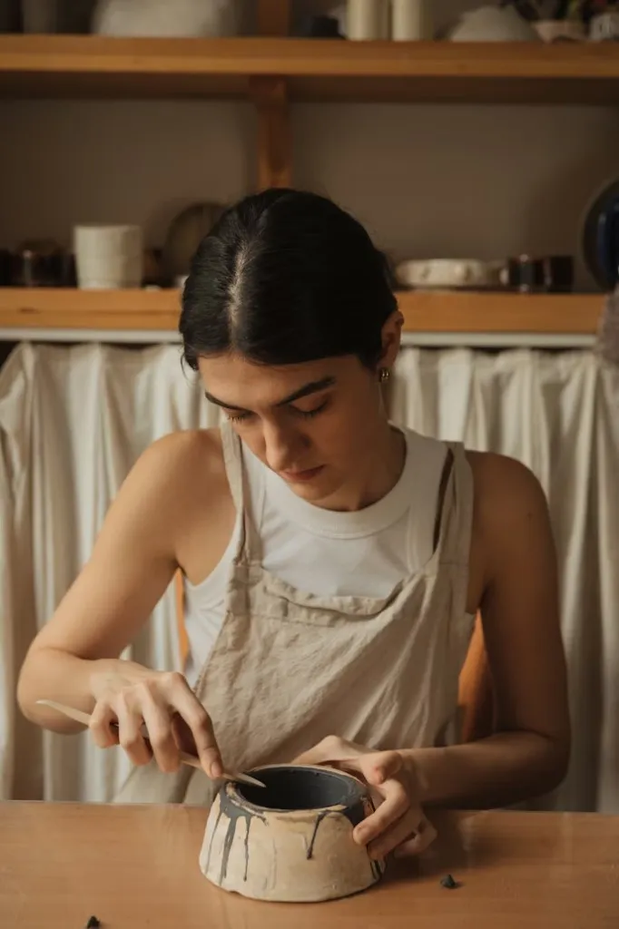 エプロン姿で陶器を仕上げる作家